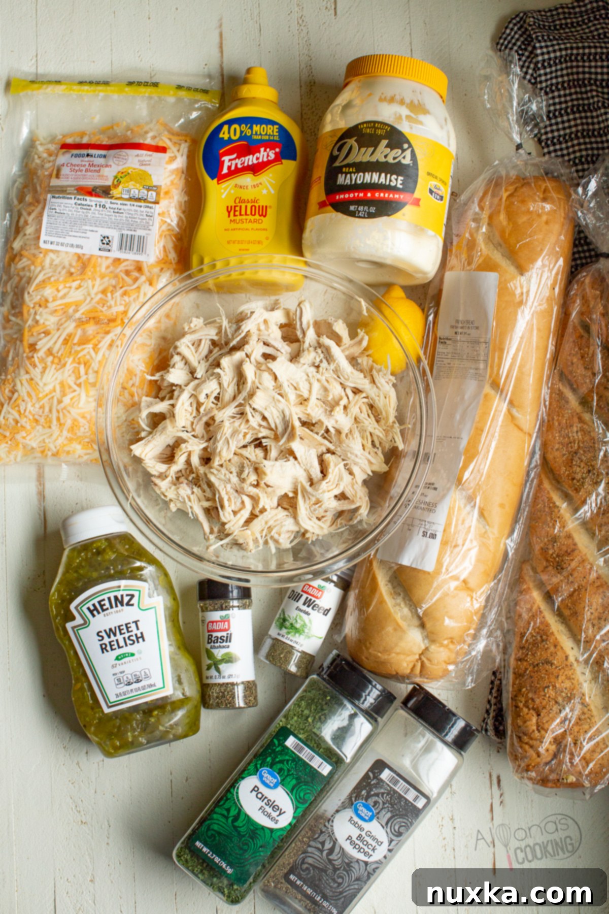 Ingredients for a chicken salad sandwich, including shredded chicken, mayonnaise, mustard, pickles, lemon juice, herbs, and cheese.