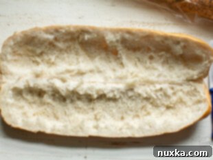 Sliced French bread roll hollowed out for chicken salad filling.