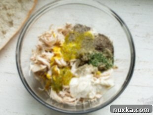 Mixing chicken salad filling in a bowl.