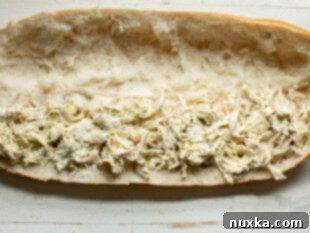 Assembled chicken salad sandwich with melted cheese topping.