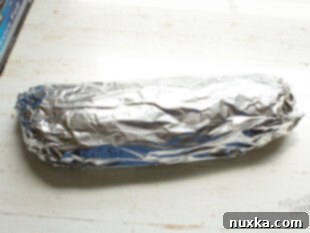 Chicken salad sandwich wrapped in foil, ready for baking.