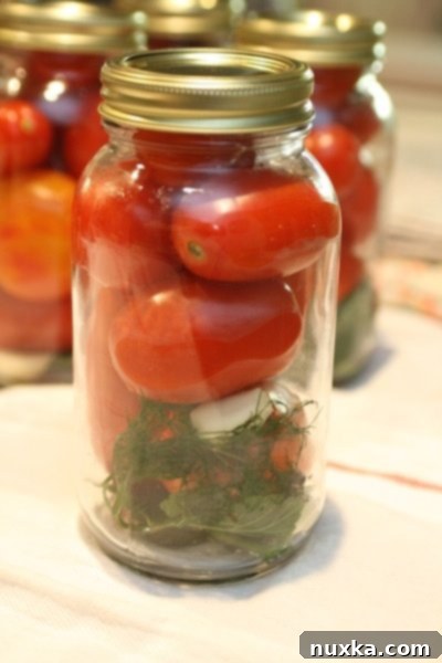 Sealed jars of Ukrainian pickled tomatoes resting on a blanket, upside down