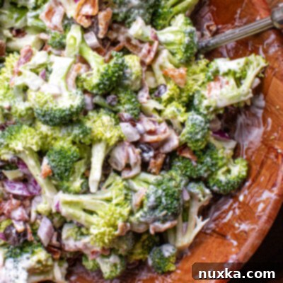 A beautiful bowl of creamy broccoli salad, garnished with crispy bacon and sweet raisins, ready to be enjoyed.