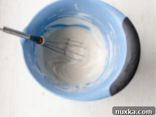 Creamy honey dressing for broccoli salad in a small bowl with a whisk.