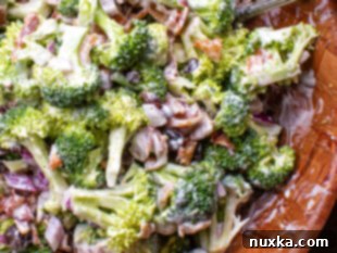 A large serving bowl filled with creamy broccoli salad, garnished and ready to serve.