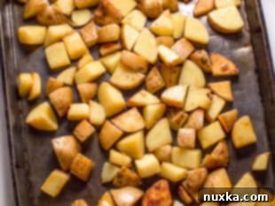 Transferring seared potatoes to a baking sheet and adding toppings.