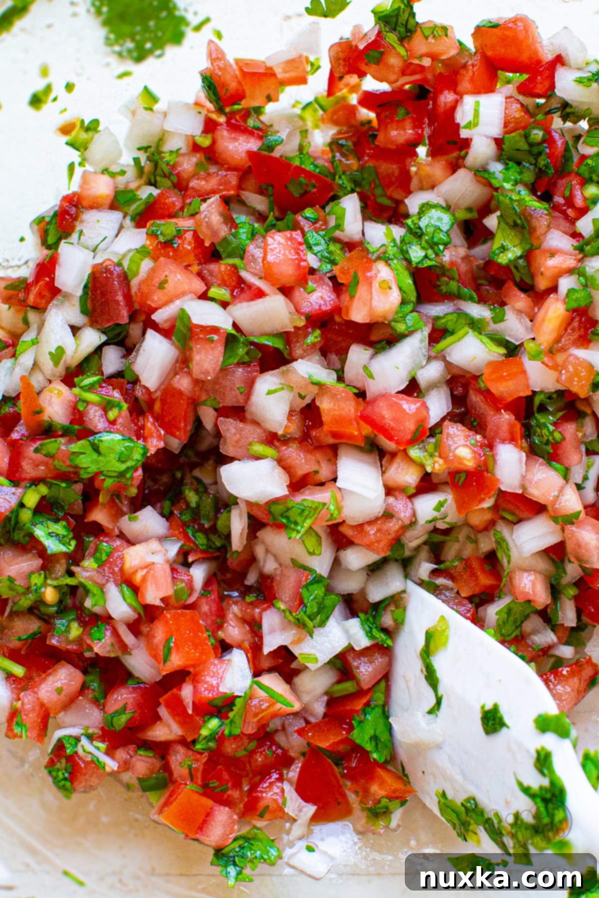 Vibrant homemade Pico de Gallo in a clear glass bowl, showcasing fresh chopped tomatoes, onions, cilantro, and a hint of green pepper.