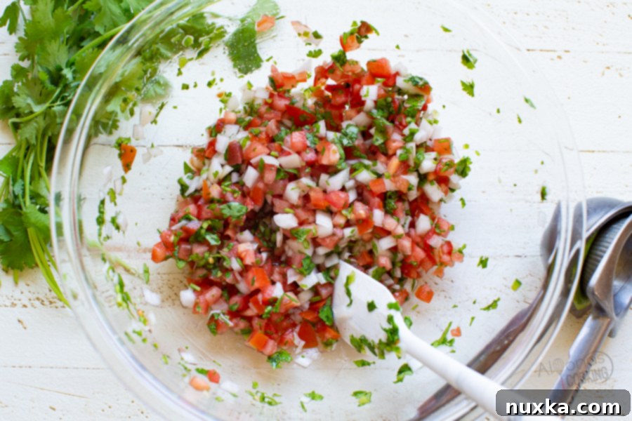 Close-up of freshly diced ingredients for Pico de Gallo, including tomatoes, onions, and green chilies, ready to be mixed.
