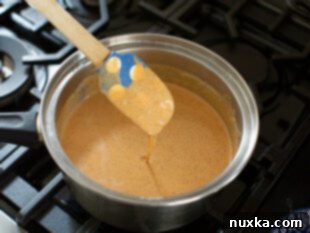 A pot of creamy homemade enchilada sauce simmering on the stovetop.