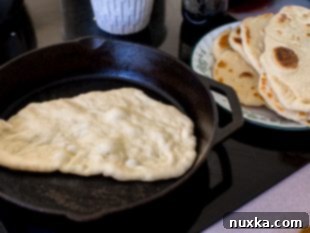 cooking naan bread on a hot skillet until golden brown
