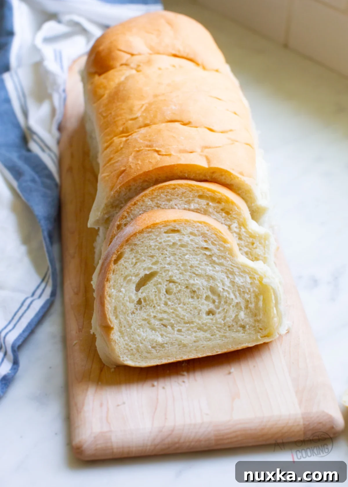 French bread recipe with a golden crust and soft interior, sliced and ready to serve on a wooden board