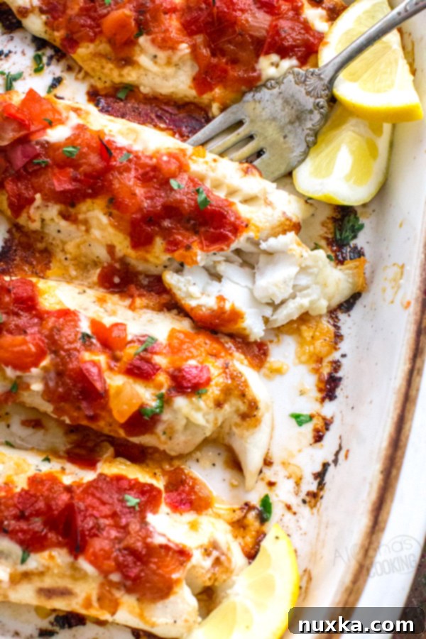 Close-up of a baked fish fillet topped with generous spoonfuls of vibrant mango peach salsa, garnished with fresh herbs, showcasing the delicious texture.