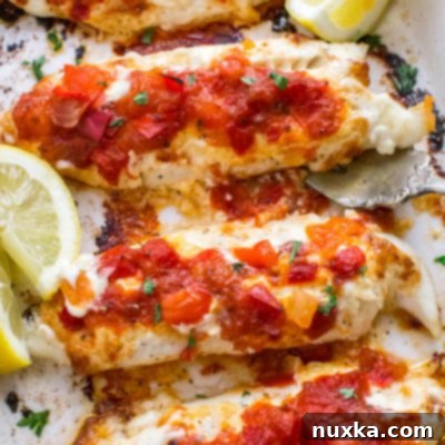 Baked fish with mango salsa served on a plate, garnished with fresh herbs.