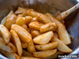 Step 2: Coating parboiled potato wedges with oil and seasoning