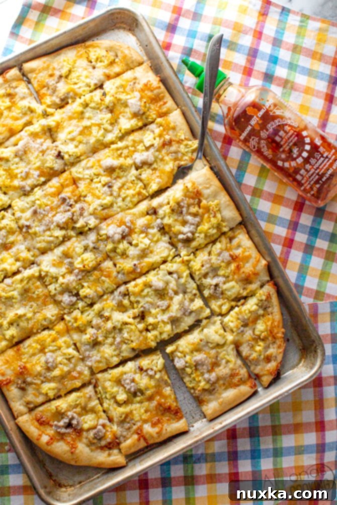 best breakfast pizza recipe on a greased sheet-pan topped with savory sausage gravy sauce, melted cheese, and fluffy scrambled eggs!