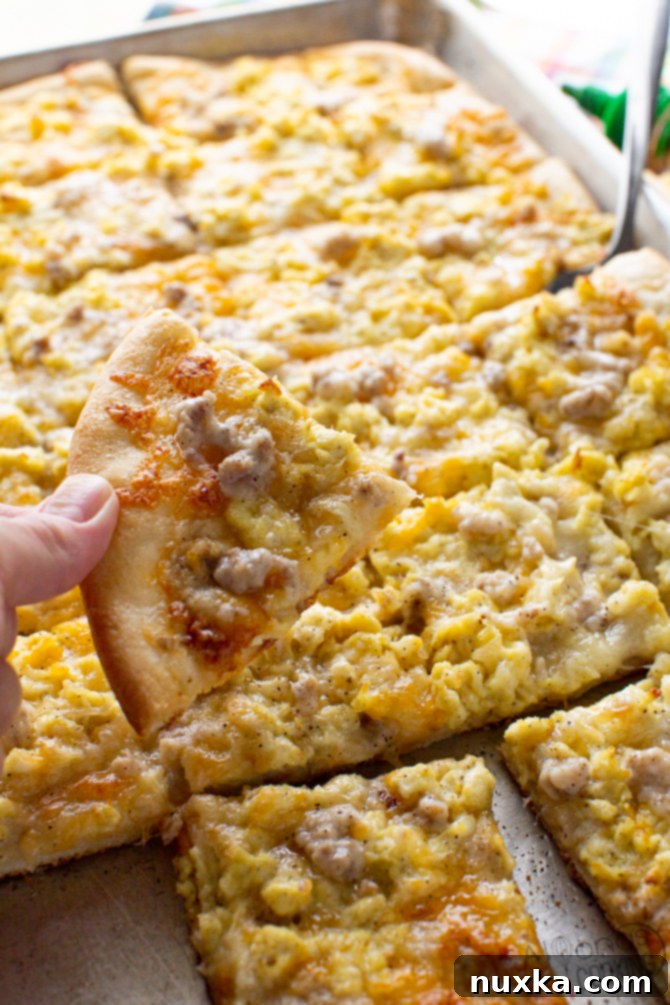a slice of homemade breakfast pizza with sausage gravy, cheese, and scrambled eggs