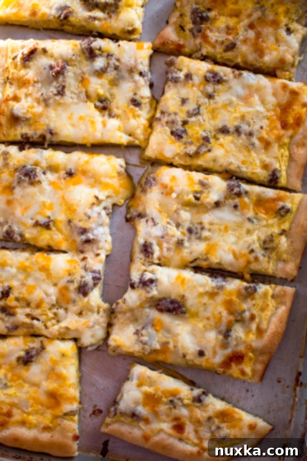 breakfast pizza like school breakfast pizza with sausage gravy sauce, cheese and raw eggs on a pan