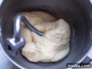 Mixing sugar, yeast, and flour into the warm milk and butter mixture for cinnamon roll dough