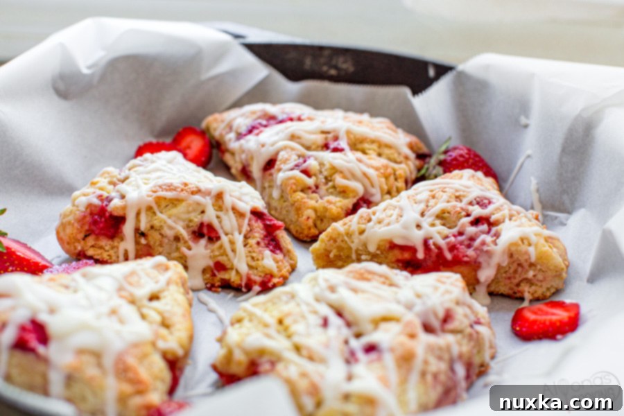 strawberry scones in a cast iron pan with parchment paper and fresh strawberries
