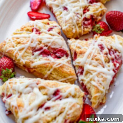 Dreamy Strawberry Cheesecake Scones 4 strawberry scones with a cream glaze and fresh strawberries that have a cream cheese batter