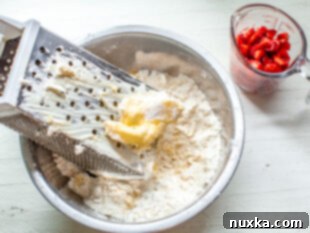 cutting the butter and cream cheese into the flour using a box grater