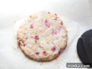 folded and patted scone dough on parchment paper