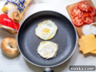 eggs in a skillet seasoned with black pepper and salt for bagel breakfast sandwiches