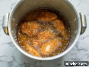 homemade crispy chicken being fried in a large pot with soybean oil