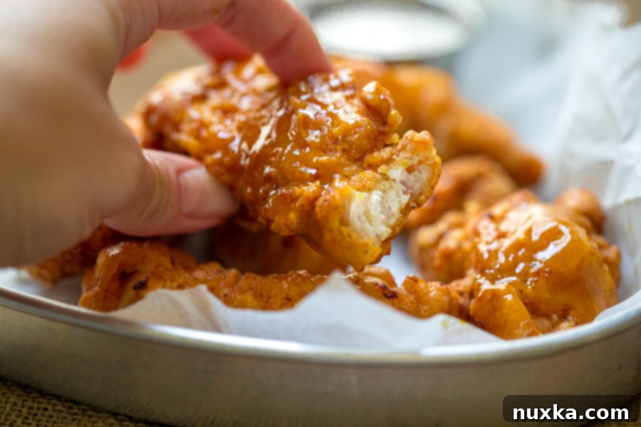 Close-up of golden boneless wings coated in a sweet Golden mustard BBQ sauce, with one wing bitten into, showing the crispy exterior and tender chicken.
