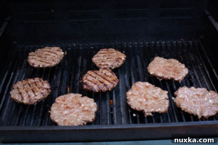 how to grill burger patties, showing three patties on a hot grill with visible grill marks