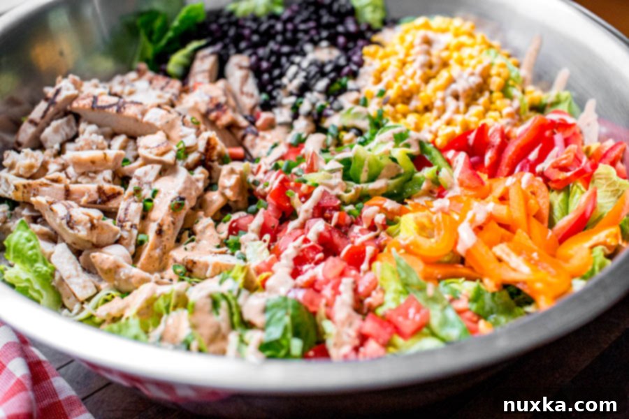 how to make southwest salad in a large mixing bowl with black beans, corn, grilled chicken, bell peppers, tomatoes, chipotle ranch dressing, and romaine lettuce