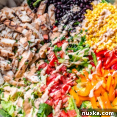 Fiesta Southwest Salad with Zesty Chipotle Ranch 4 southwest salad in a large mixing bowl with black beans, corn, grilled chicken, bell peppers, tomatoes, chipotle ranch dressing, and romaine lettuce