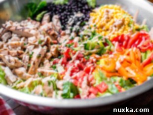 how to make southwest salad in a large mixing bowl with black beans, corn, grilled chicken, bell peppers, tomatoes, chipotle ranch dressing, and romaine lettuce