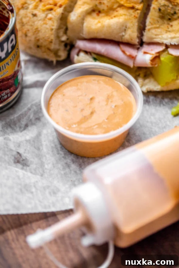 Subway's Chipotle Southwest Sauce in a container and a squeezable bottle, next to a delicious sandwich, perfectly replicating the iconic restaurant flavor at home.