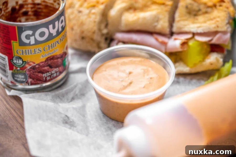 A bowl of freshly made homemade Subway Chipotle Southwest Sauce, ready to be enjoyed with a ham sandwich, showcasing its creamy texture and vibrant color.
