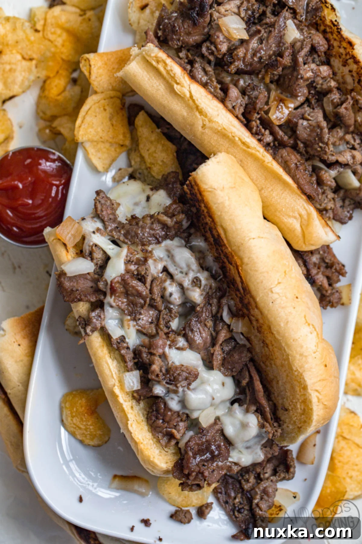 Close-up image of a classic Philly cheesesteak sandwich on a plate, featuring tender sliced beef, melted provolone cheese, and caramelized fried onions.