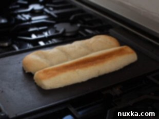 image of submarine bread (hero rolls) being toasted face down on a hot griddle for Philly CheeseSteaks