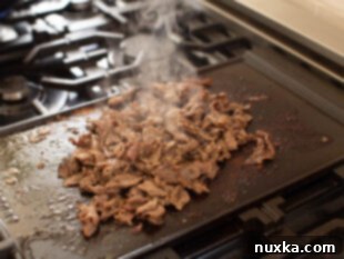 image of cooked beef shavings on a hot griddle for Philly Cheesesteaks