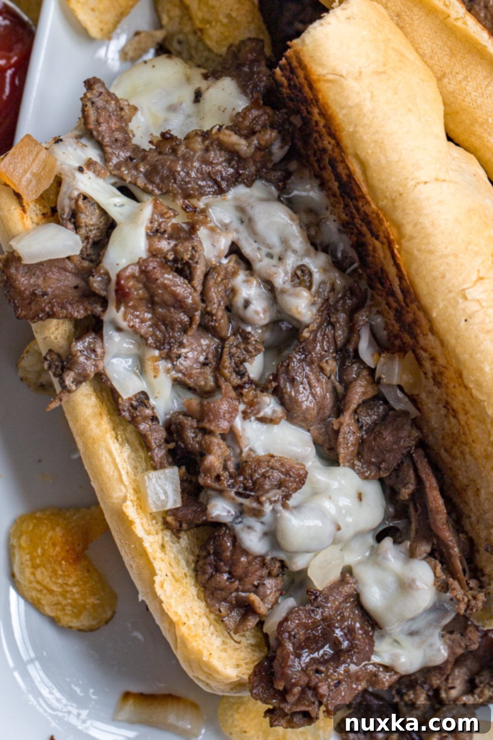 Appetizing image of a finished Philly Cheesesteak sandwich, highlighting the melted provolone cheese and tender fried onions peeking from under the sliced beef, all encased in a perfectly toasted roll.
