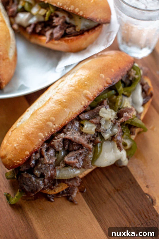 Authentic Philly Cheesesteak Sandwich with Onions and Peppers Image of a beautifully assembled Philly Cheesesteak Sandwich on a cutting board, garnished with fresh onions and bell peppers, highlighting the savory filling within a toasted hoagie roll.