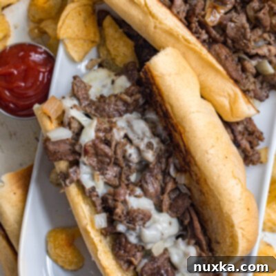 Philadelphia's Iconic Steak Hoagie 2 image of Philly cheesesteaks on a plate made from sliced beef, provolone cheese, and fried onions