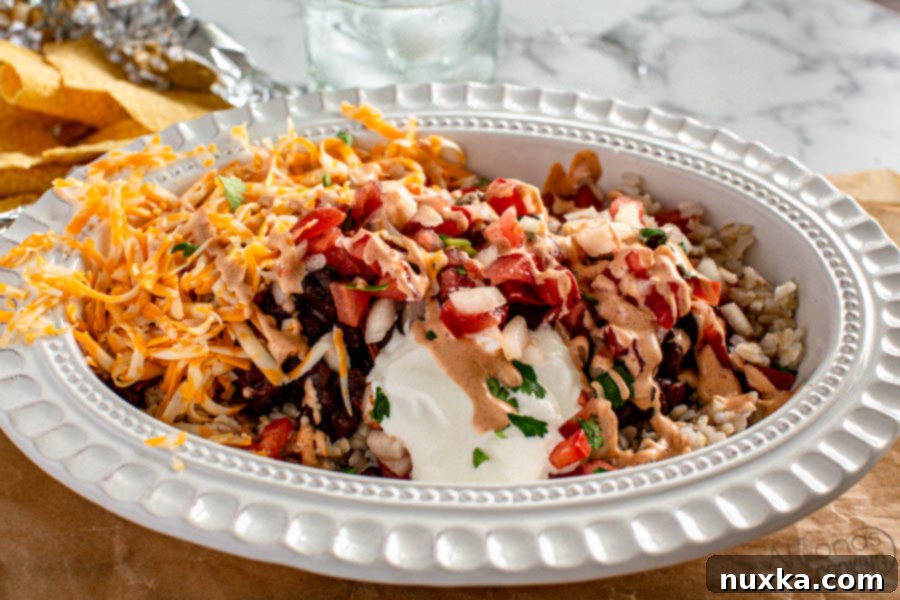 An appetizing burrito bowl, filled with fluffy rice, tender black beans, vibrant pico de gallo, a sprinkle of cheese, and fresh cilantro, presented in an elegant oval dish for a hearty and healthy meal.