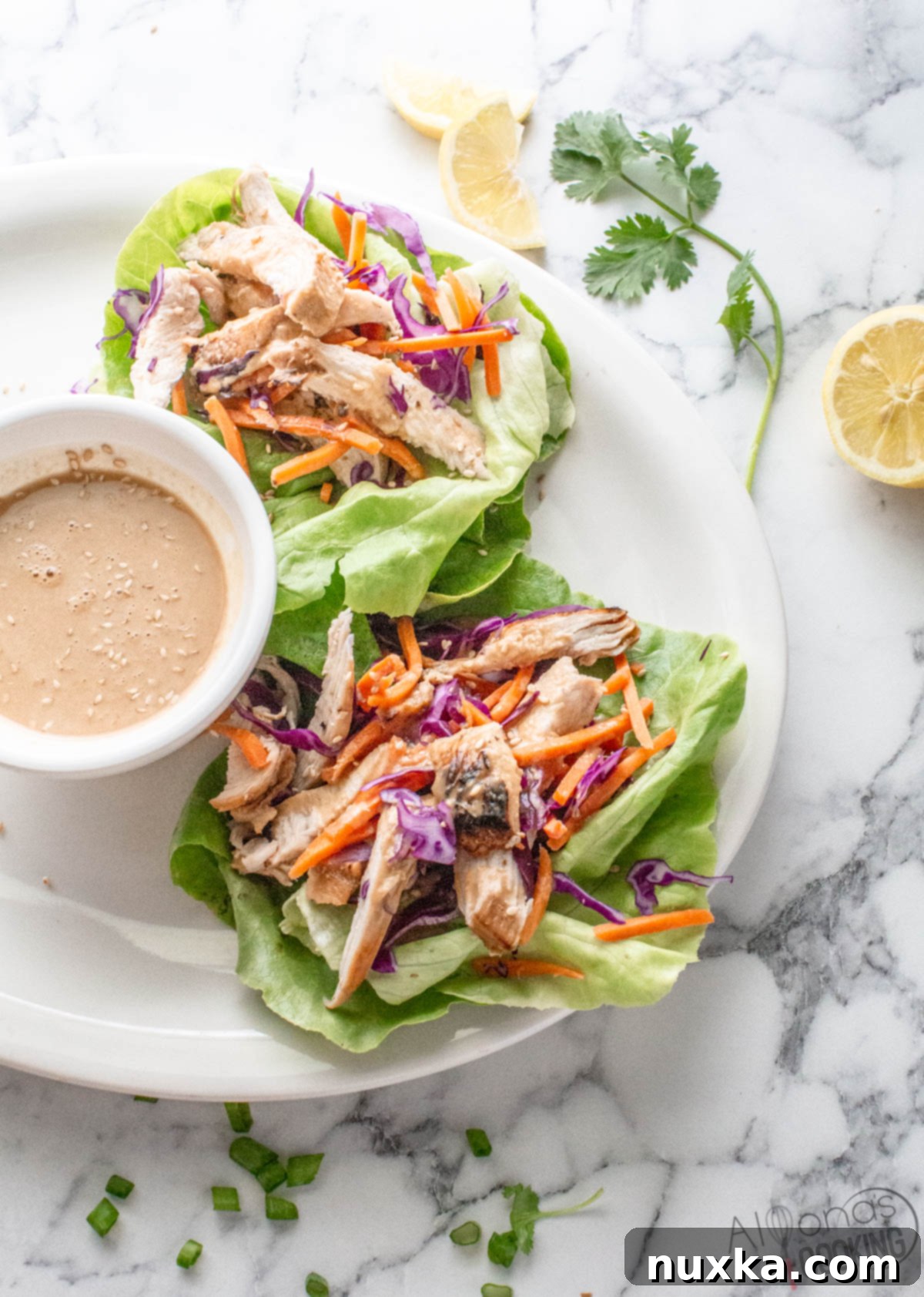 Close-up of chicken lettuce wraps with peanut dressing and a side of chili sauce