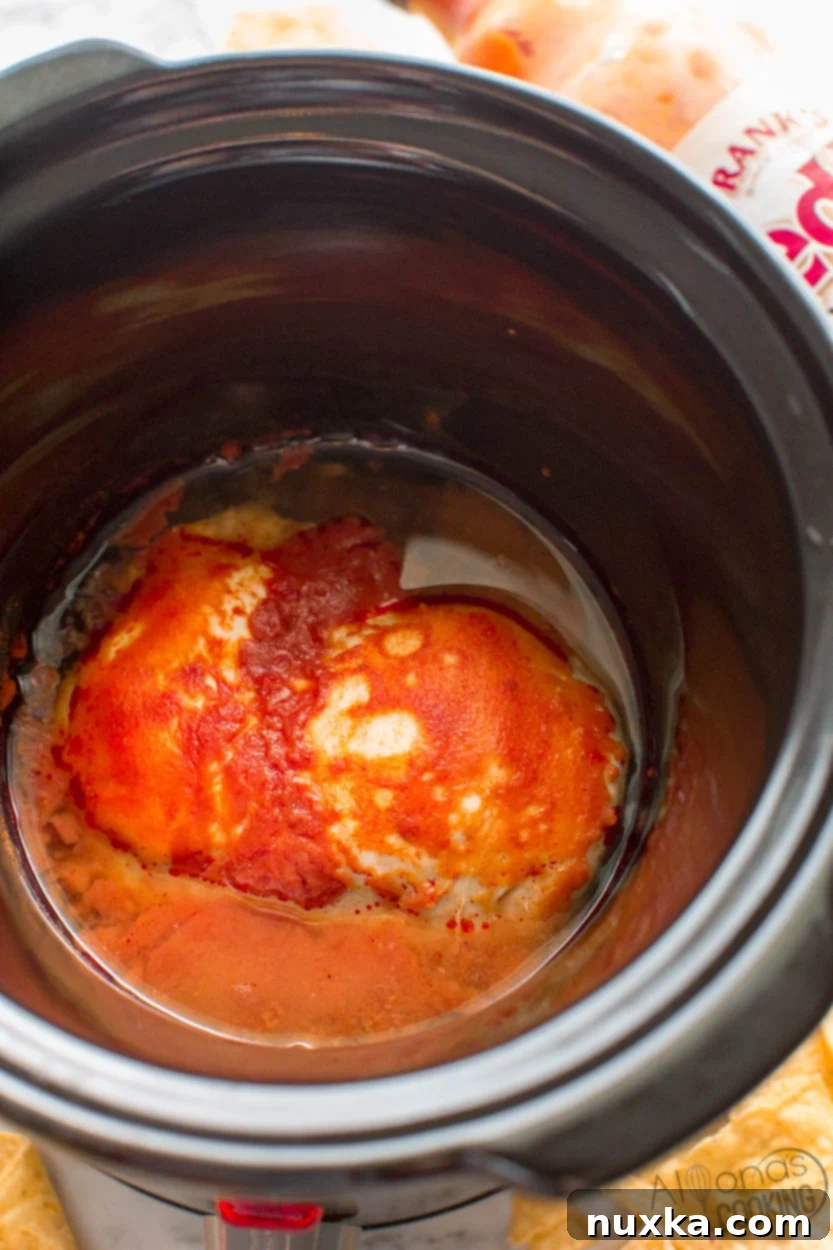 Slow cooker buffalo chicken that can be used for a wide range of dishes like salads, sandwiches, and dips, showcasing its versatility.