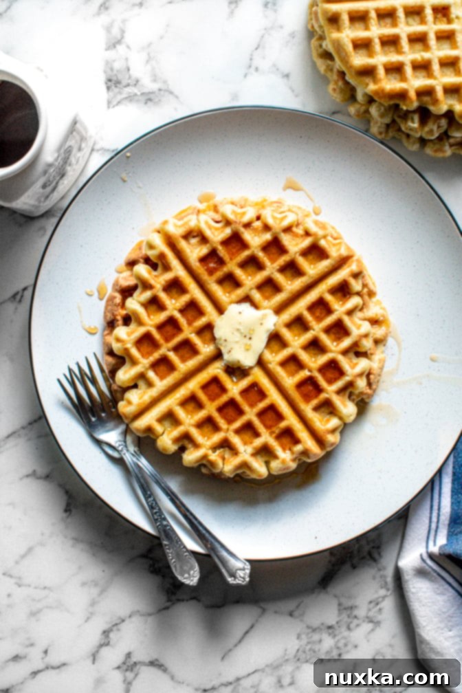 Fluffy homemade pumpkin waffles stacked on a plate, garnished with cinnamon and syrup, perfect for a fall breakfast.