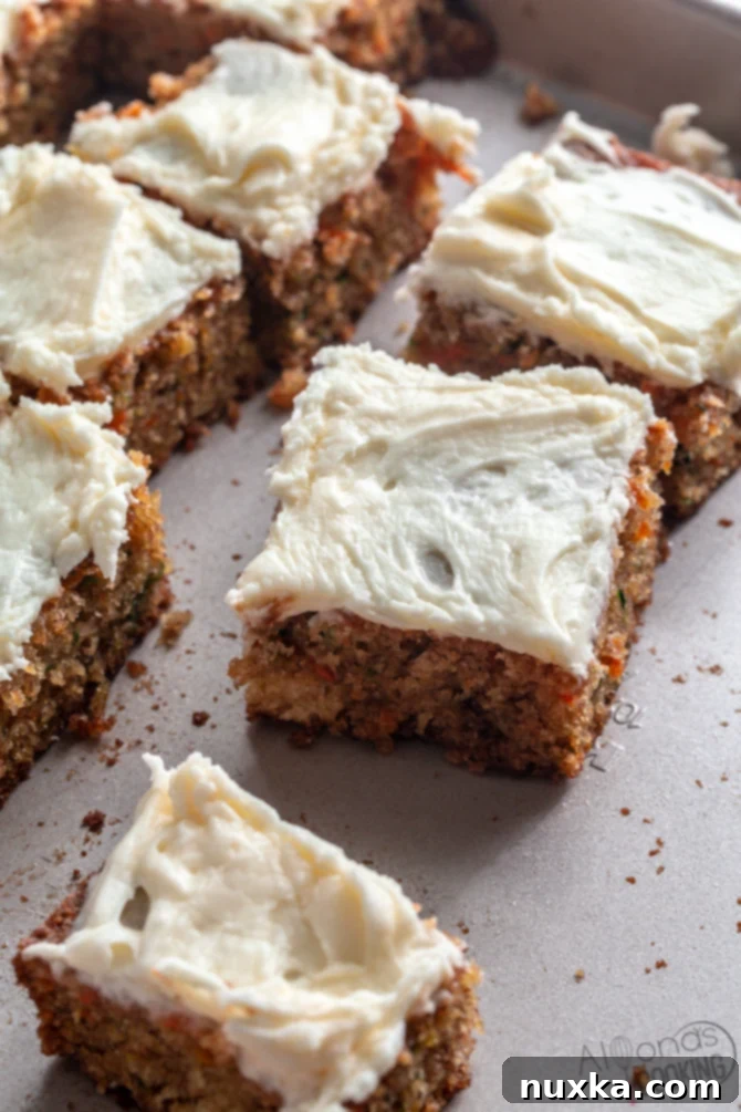 shredded carrot and zucchini cake made in a sheet pan, topped with cream cheese frosting