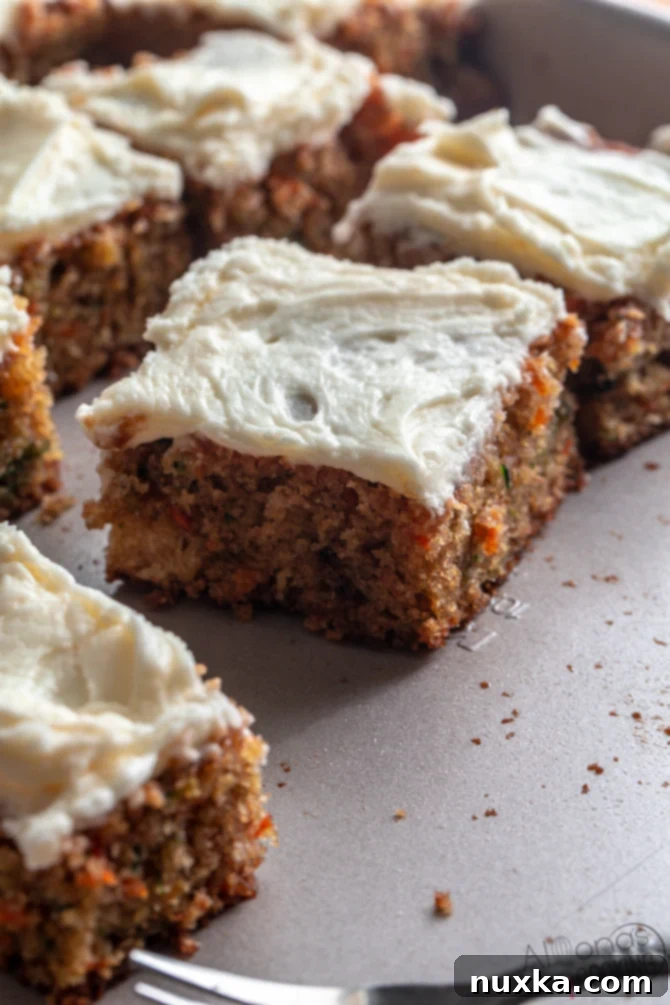 carrot and zucchini spice cake with cream cheese frosting, sliced into bars