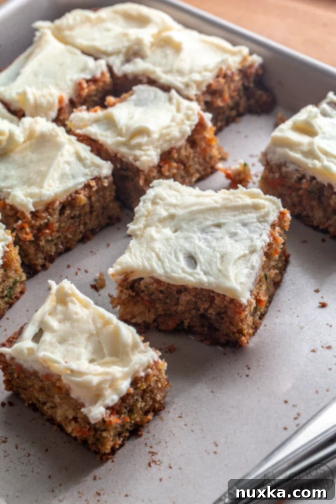 sliced carrot and zucchini cake with cream cheese frosting, garnished with nuts
