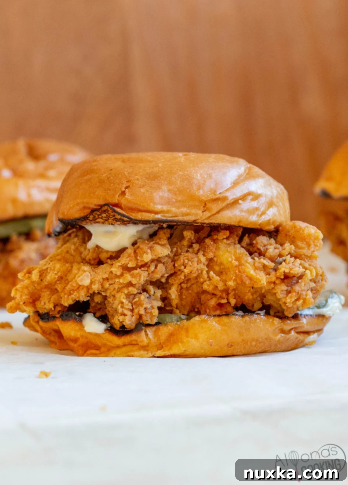 How to make a crispy homemade Popeyes chicken sandwich with a step-by-step tutorial, showing the golden fried chicken, pickles, and mayo on a brioche bun.