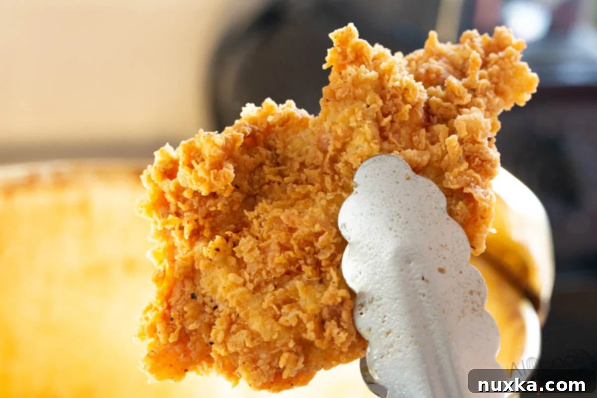 An image of perfectly fried chicken pieces, golden brown and crispy, ready to be assembled into a homemade Popeyes chicken sandwich.